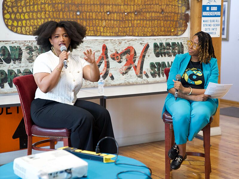 Kim Lewis of CurlMix speaks into a microphone during the Fireside Chat with CJ Harris.