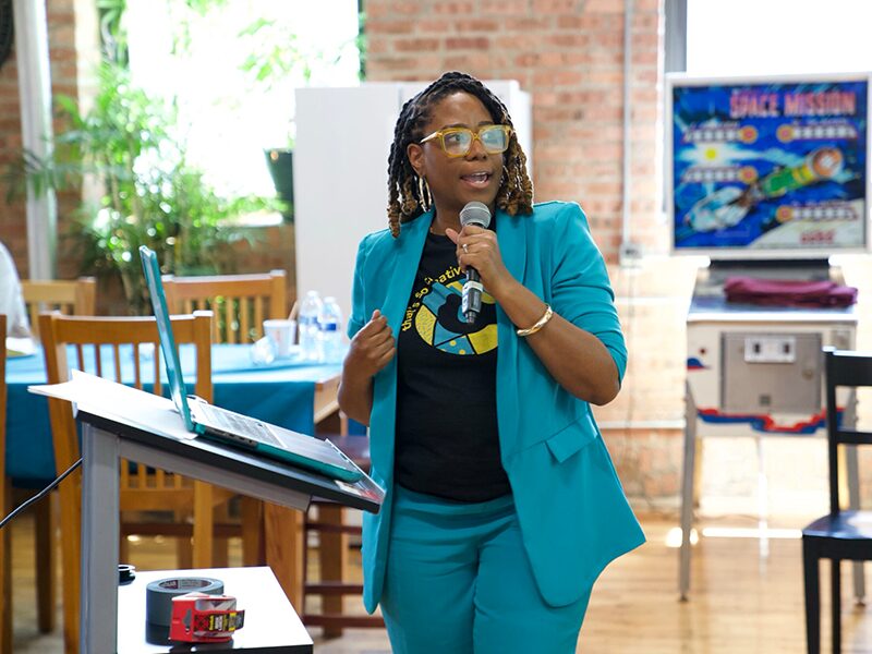 CJ Harris speaks into a microphone during her segment about the use of AI in marketing and small business.