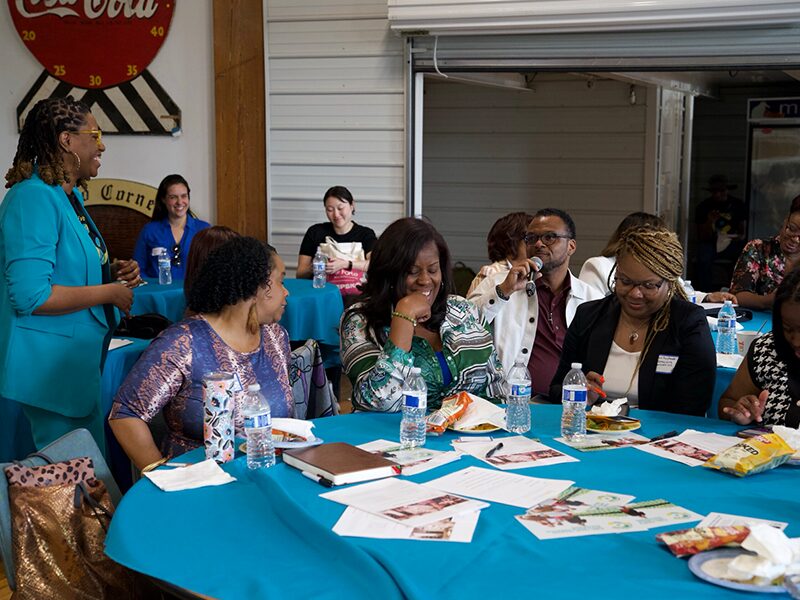 Attendees smile and laugh as an attendee speaks on a microphone during the Q & A segment after the lecture.